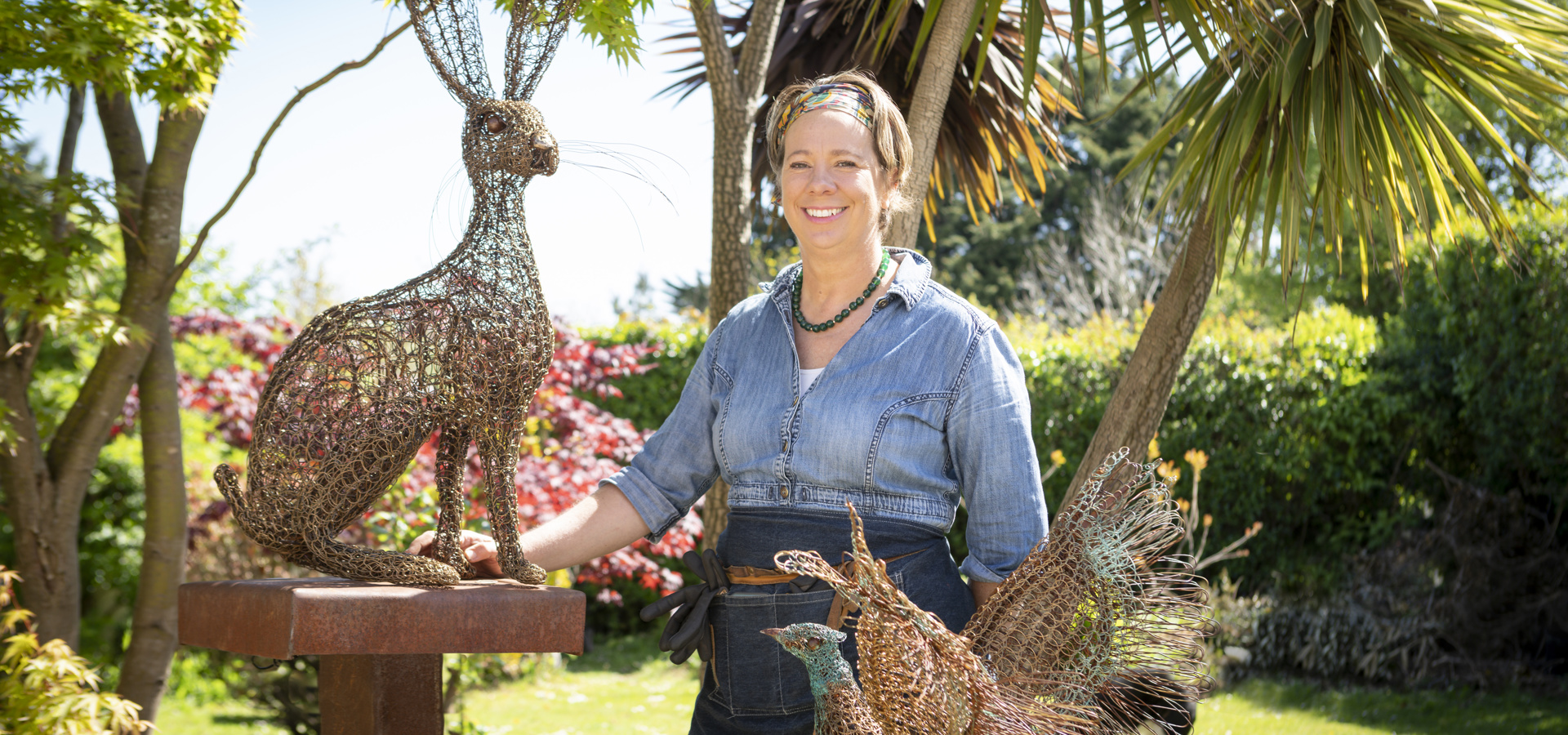 Artist outdoors with woven willow hare and pheasant sculptures for the Archers Wood commission