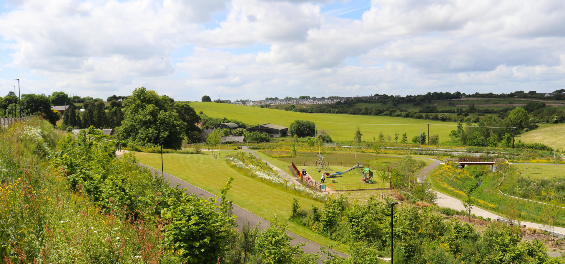 Landscaped open green space with footpaths and a play area at a Cairn development