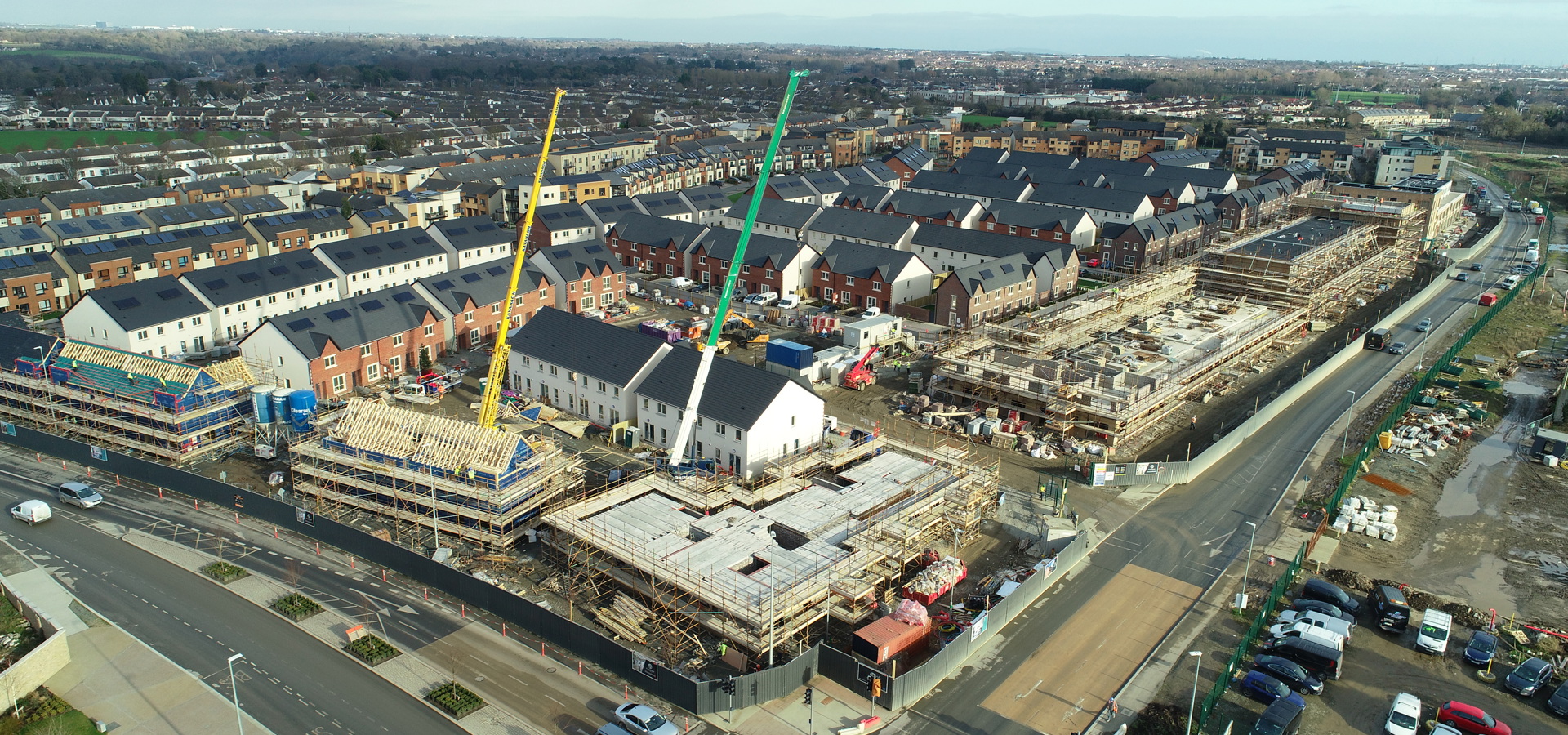 Aerial view of a Cairn housing development under construction, with terraced homes and tower cranes