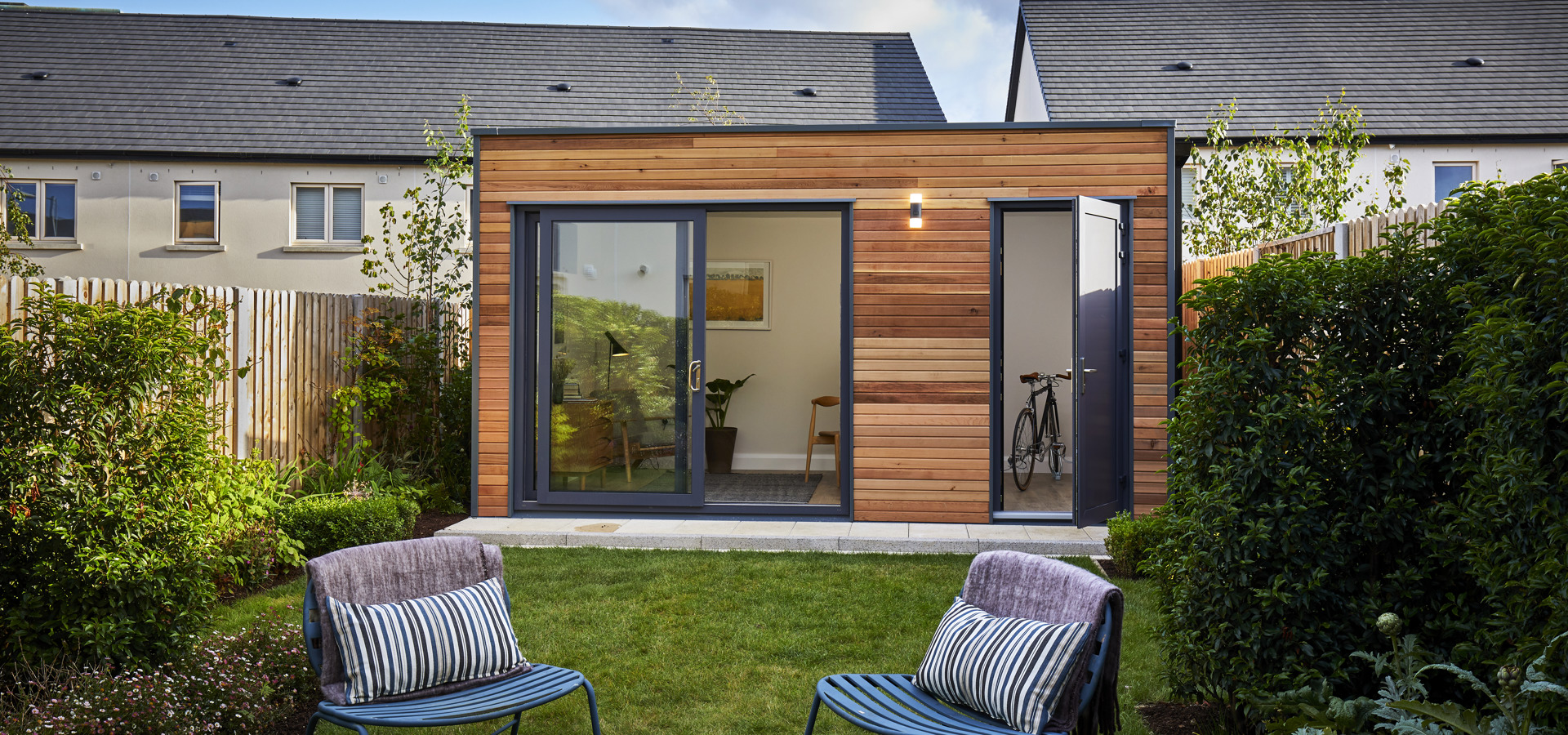 Garden office pod with glazed doors and two chairs on the lawn of a back garden