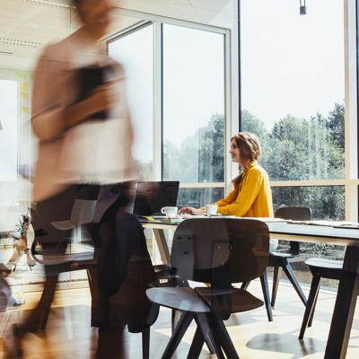 Modern open-plan office with glass partitions and people moving between desks