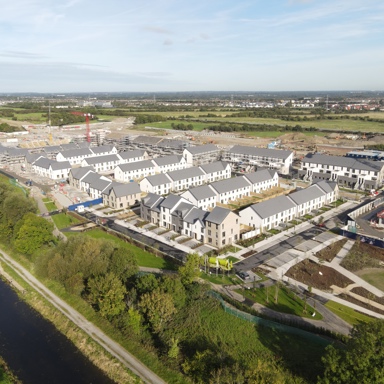 Aerial view of a new residential housing development site under construction next to a river and green space.
