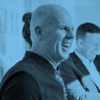 Blue-tinted image of Cairn colleagues laughing during a meeting