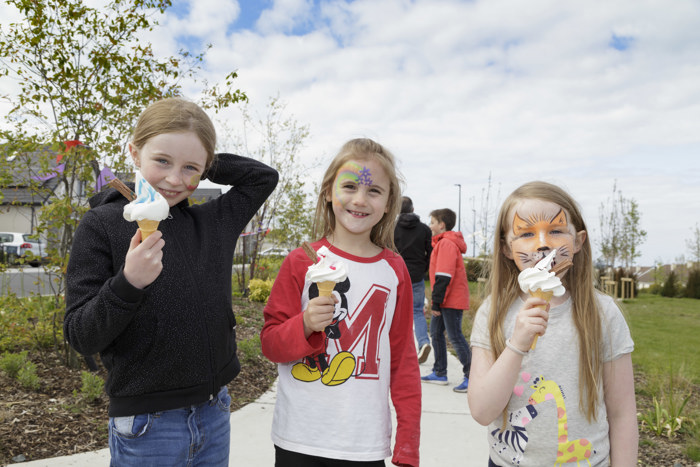 Three children with ice creams and face paint at an outdoor street feast event