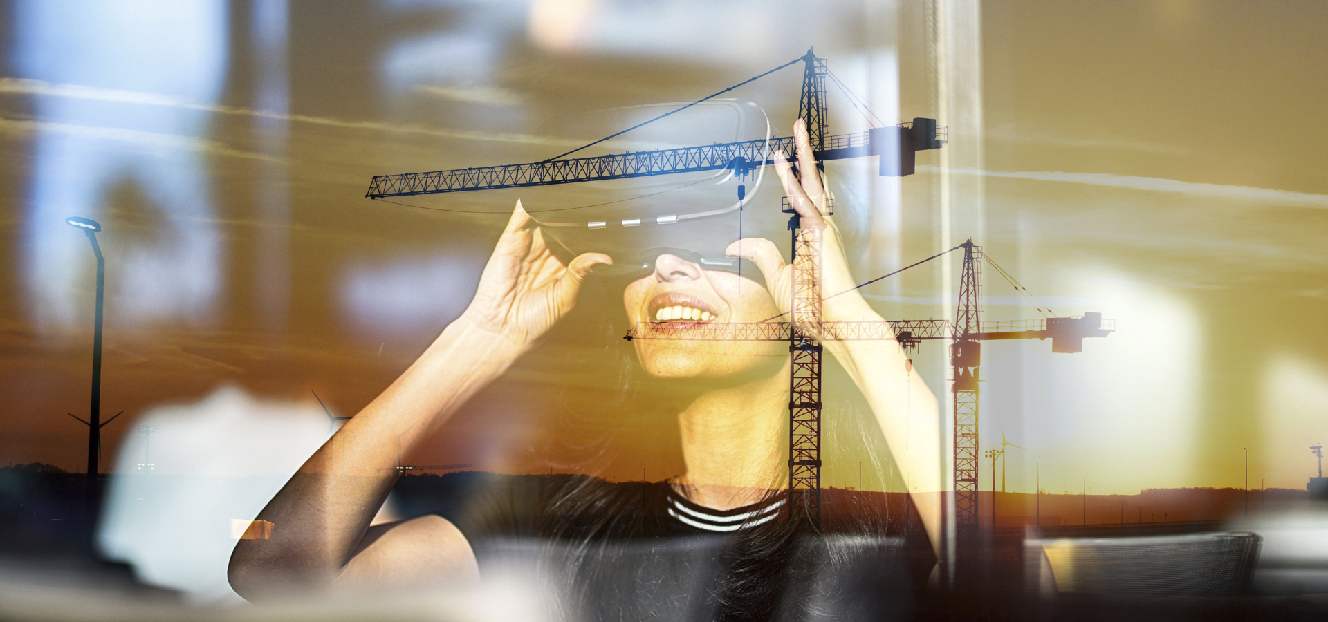 Double-exposure stock image blending a person at a desk with construction cranes
